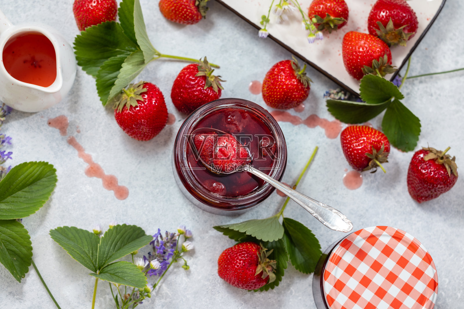 新鲜的自制草莓果酱在玻璃罐中，在一个浅背景。照片摄影图片