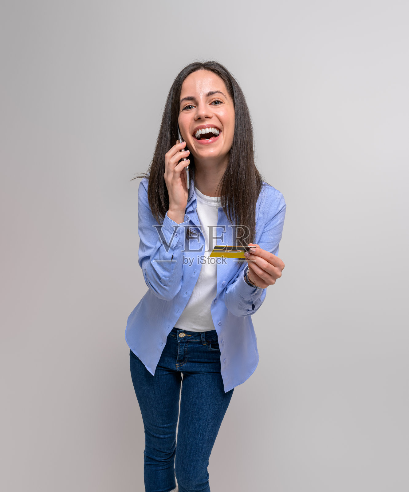笑着的女企业家拿着信用卡，在白色背景下用手机说话照片摄影图片