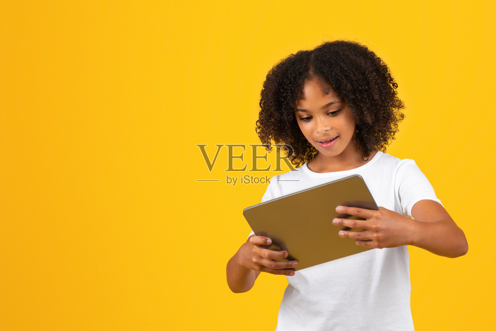 穿着白色t恤的开朗的非洲裔美国女孩在平板电脑上玩网络游戏，看视频课程照片摄影图片