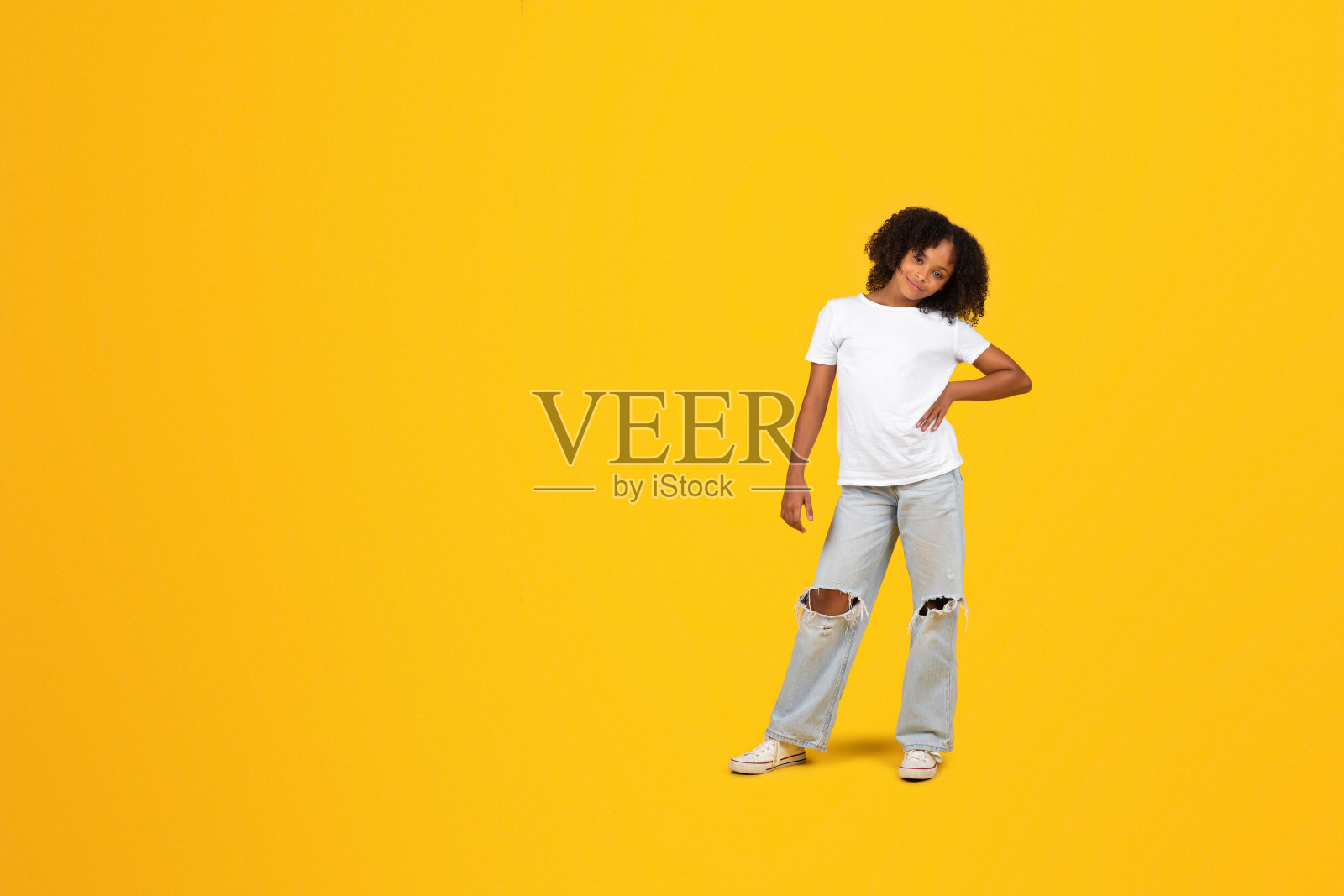 穿着白色t恤的快乐、自信、卷曲的黑人女学生看着镜头照片摄影图片