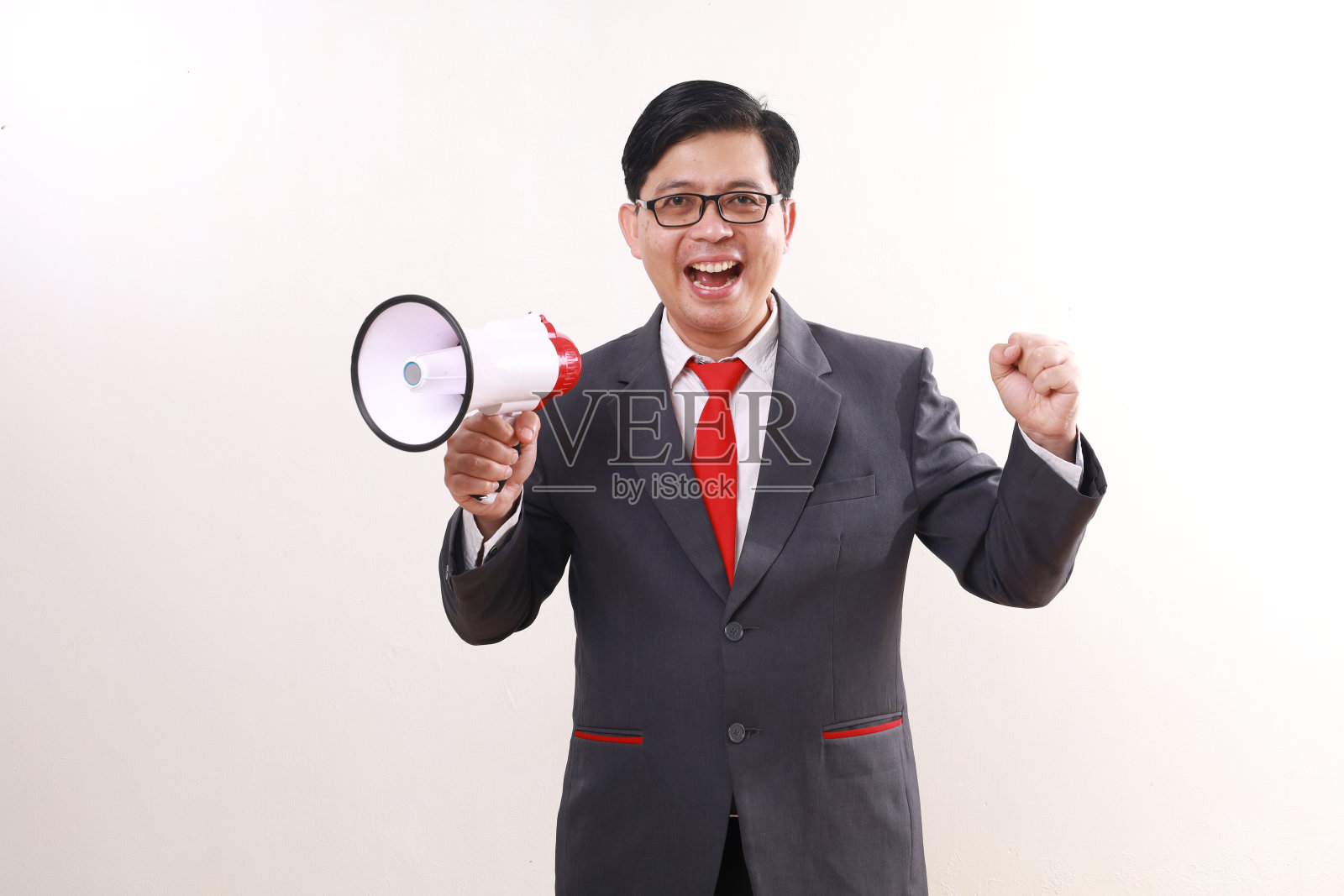快乐兴奋的亚洲商人庆祝成功，同时拿着扩音器和拳头照片摄影图片