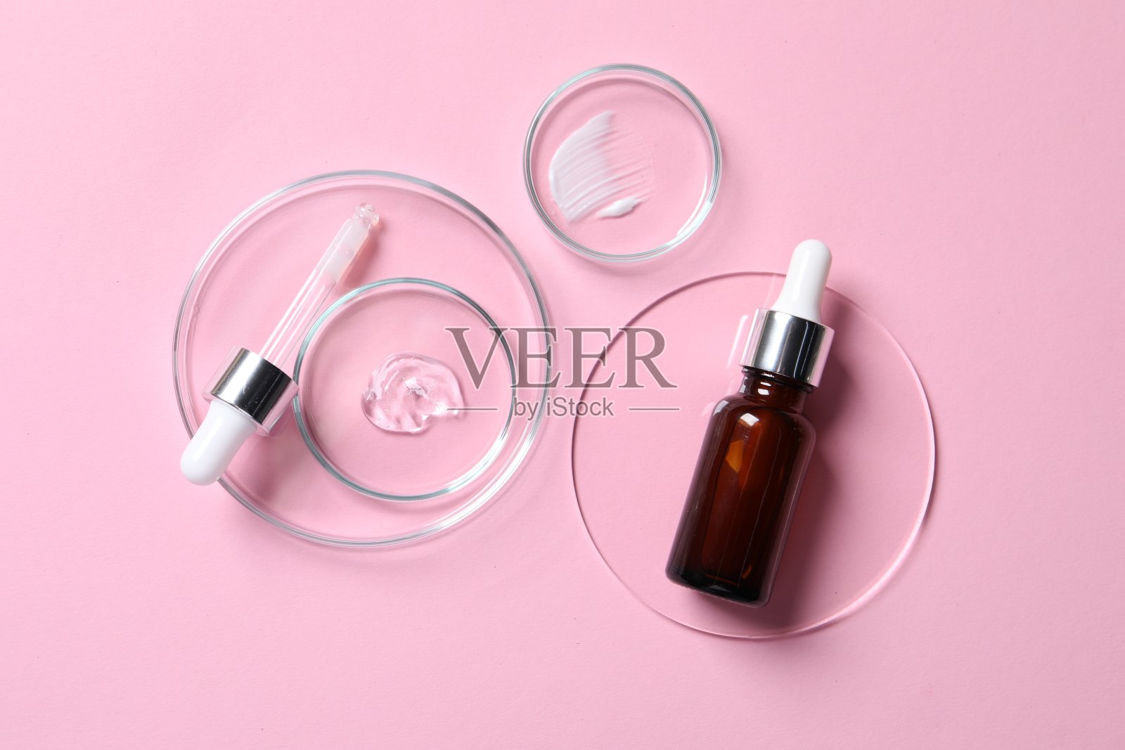 一瓶化妆品血清和培养皿样品粉红色的背景，平躺照片摄影图片