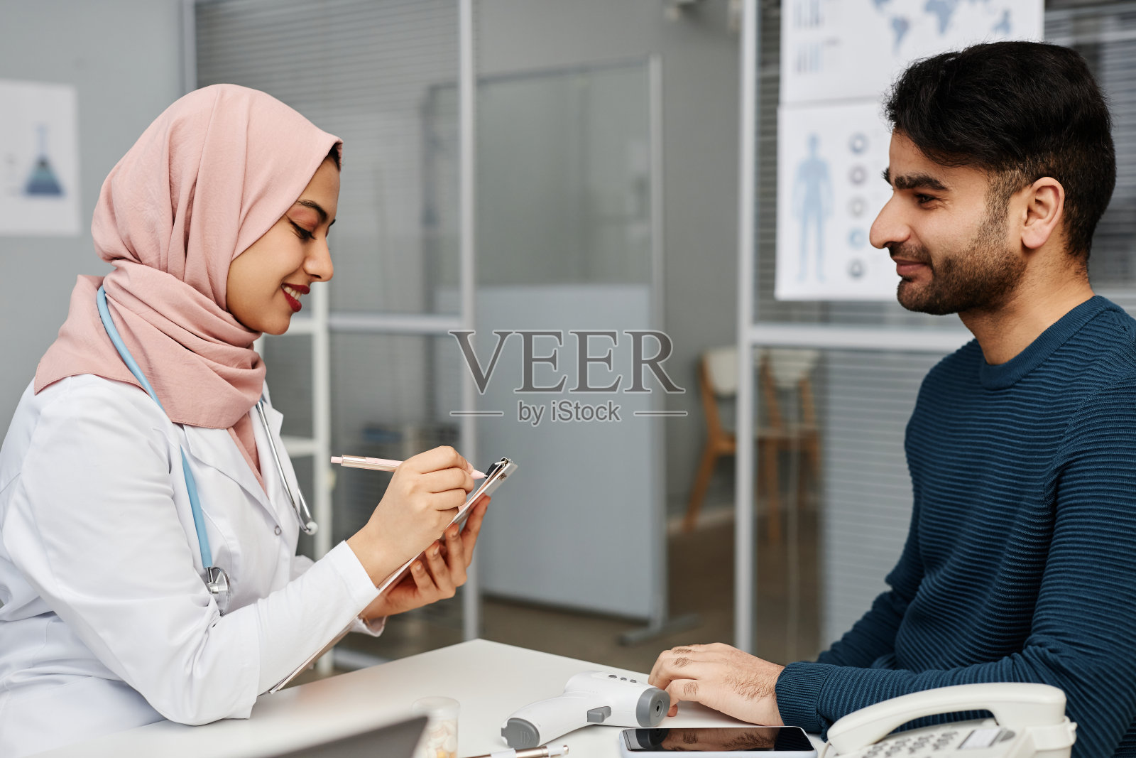 诊所里微笑的穆斯林医生和病人照片摄影图片