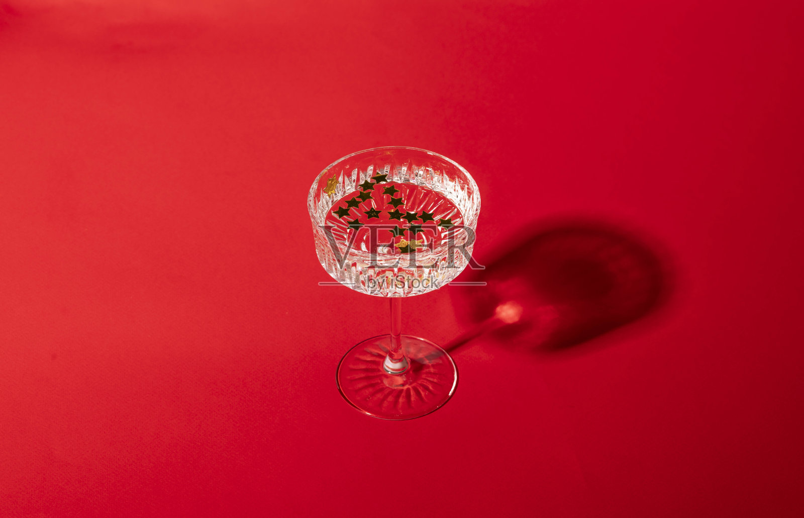 圣诞派对的概念，一杯香槟，葡萄酒和金色的星星纸屑在玻璃。圣诞晚会的喜庆背景照片摄影图片