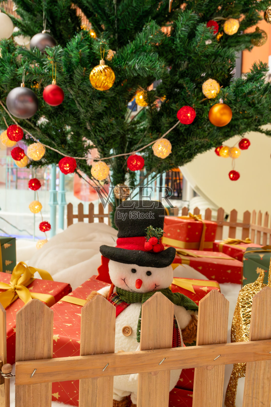 一个可爱的雪人在礼物盒和圣诞树前垂直构图照片摄影图片