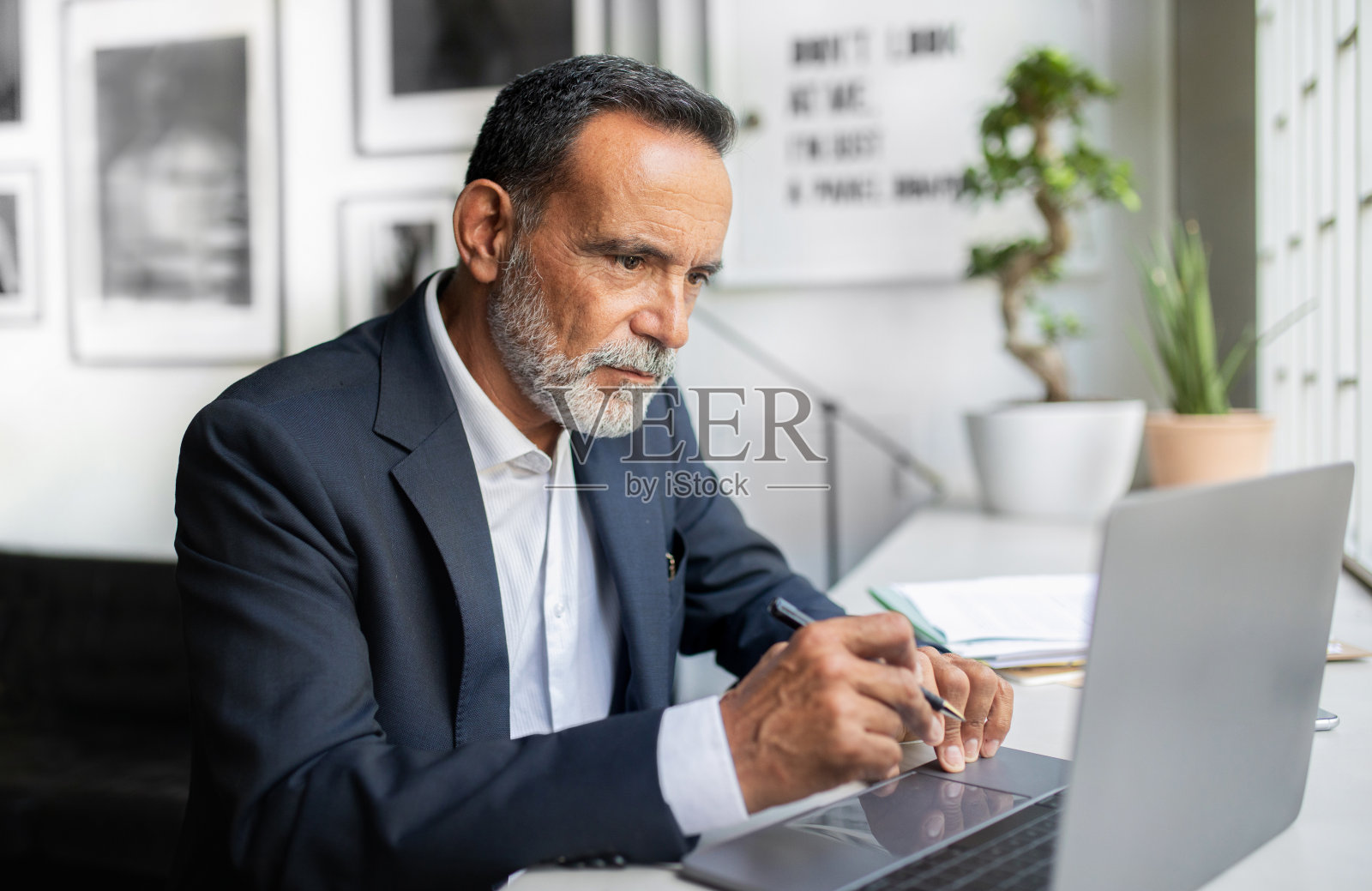 严肃自信的欧洲高级西装商人看着笔记本电脑，在办公室创造解决方案照片摄影图片