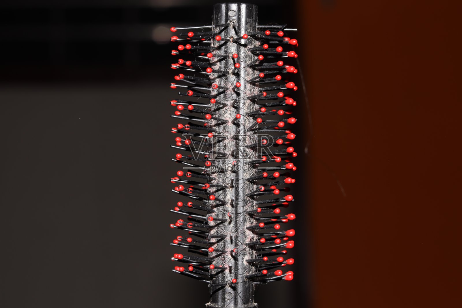 一个红黑相间的圆筒形圆锥体的特写，中间夹着几缕头发，选择性聚焦照片摄影图片