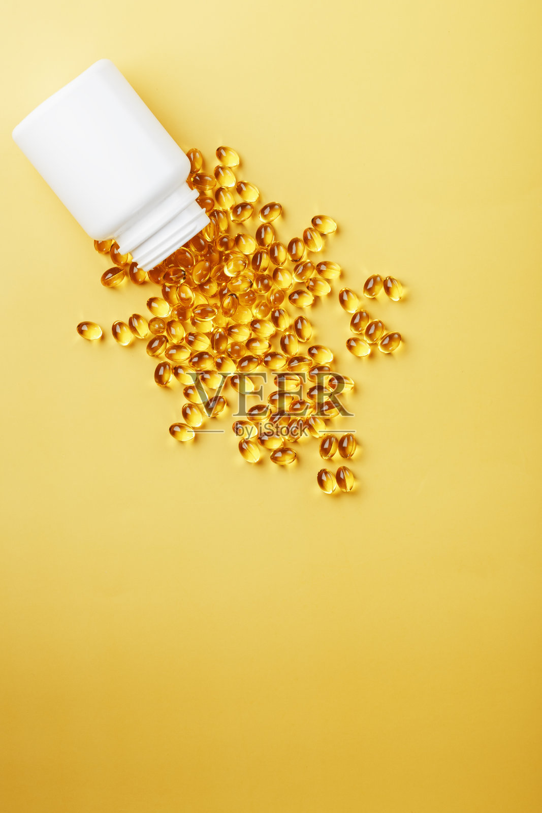 金色的Omega-3鱼油胶囊从一个黄色背景的罐子里倒出来照片摄影图片