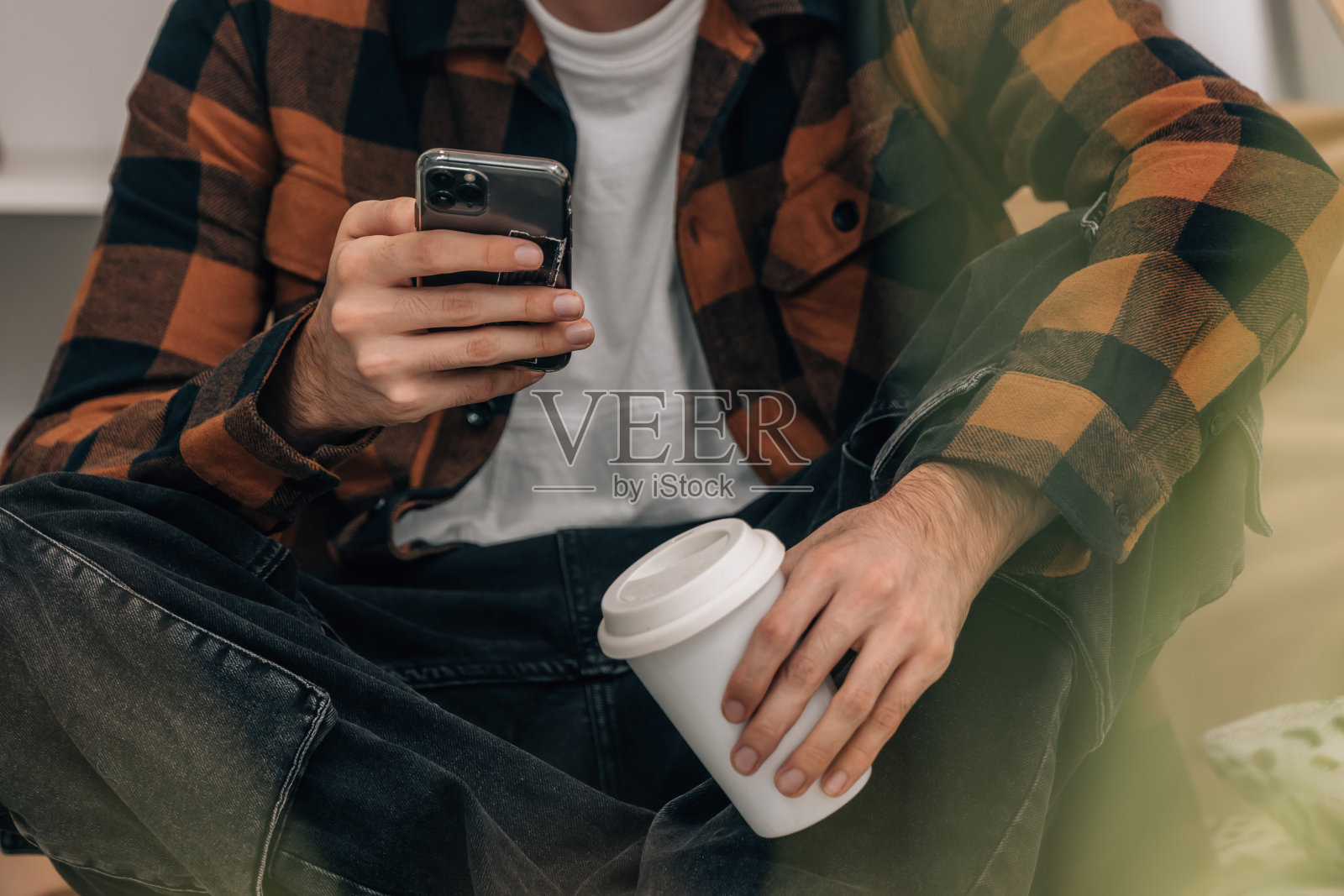 年轻人手持手机和杯子的特写镜头照片摄影图片