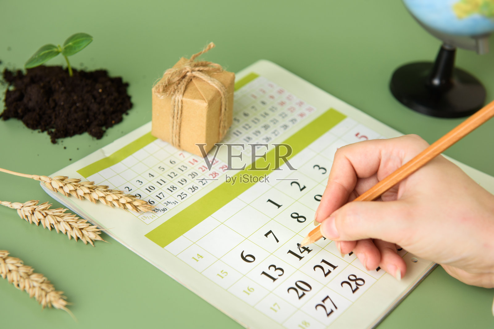 一个女人的手在日历上圈着日期。4月14日是地球日。爱护环境的理念照片摄影图片