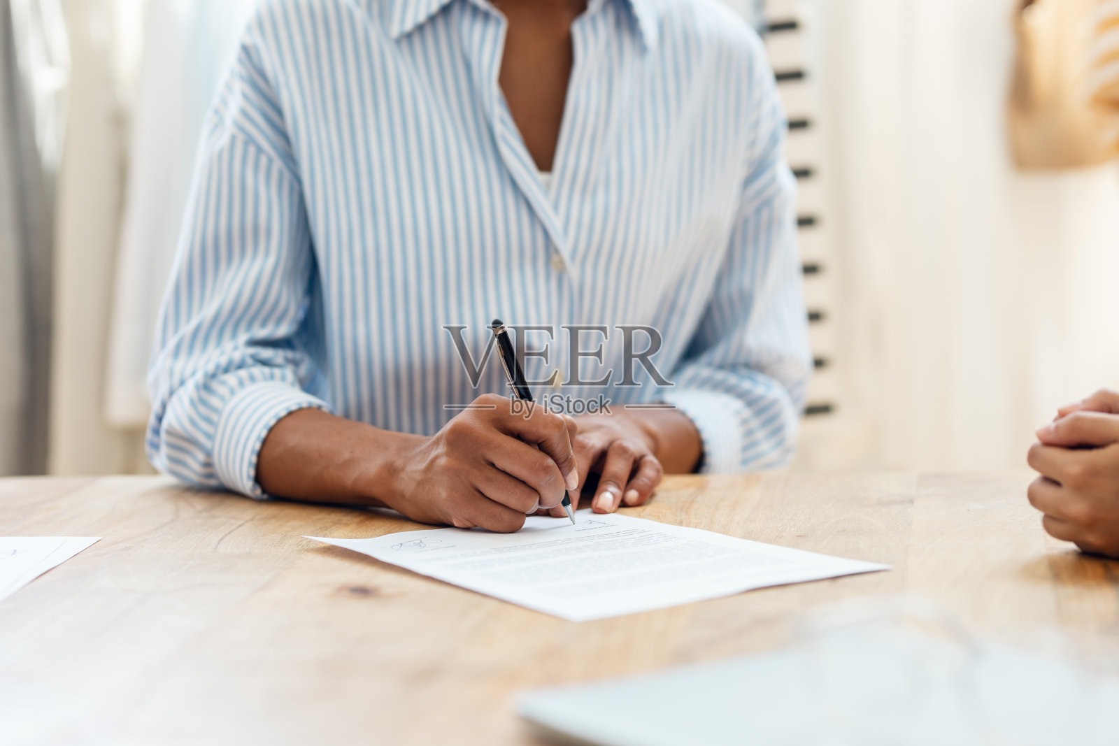 两位女服装设计师在缝纫车间签订协议合同。照片摄影图片