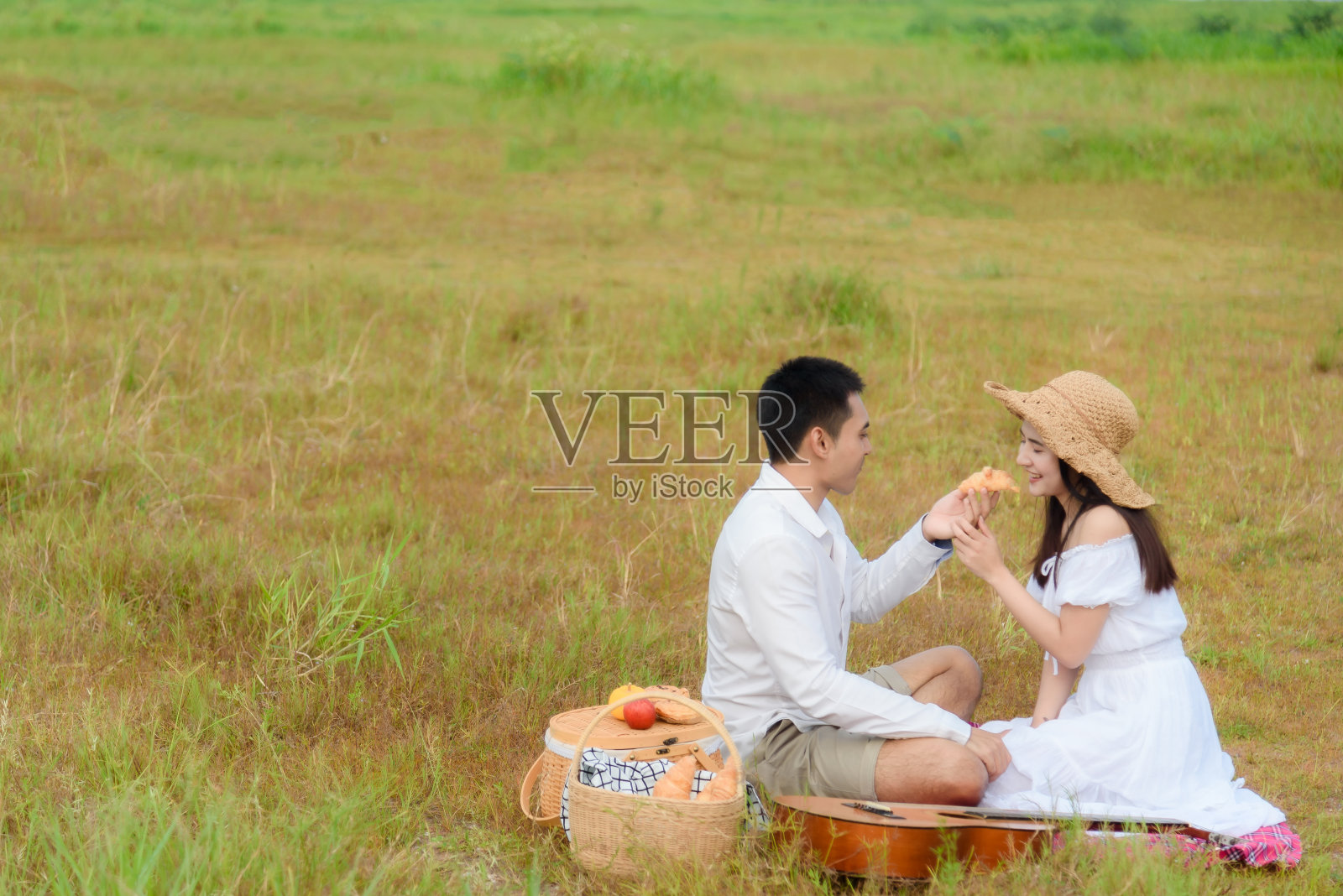 一对亚洲男人和女人在以山为背景的草地中间散步。假期里的野餐和放松的早晨照片摄影图片