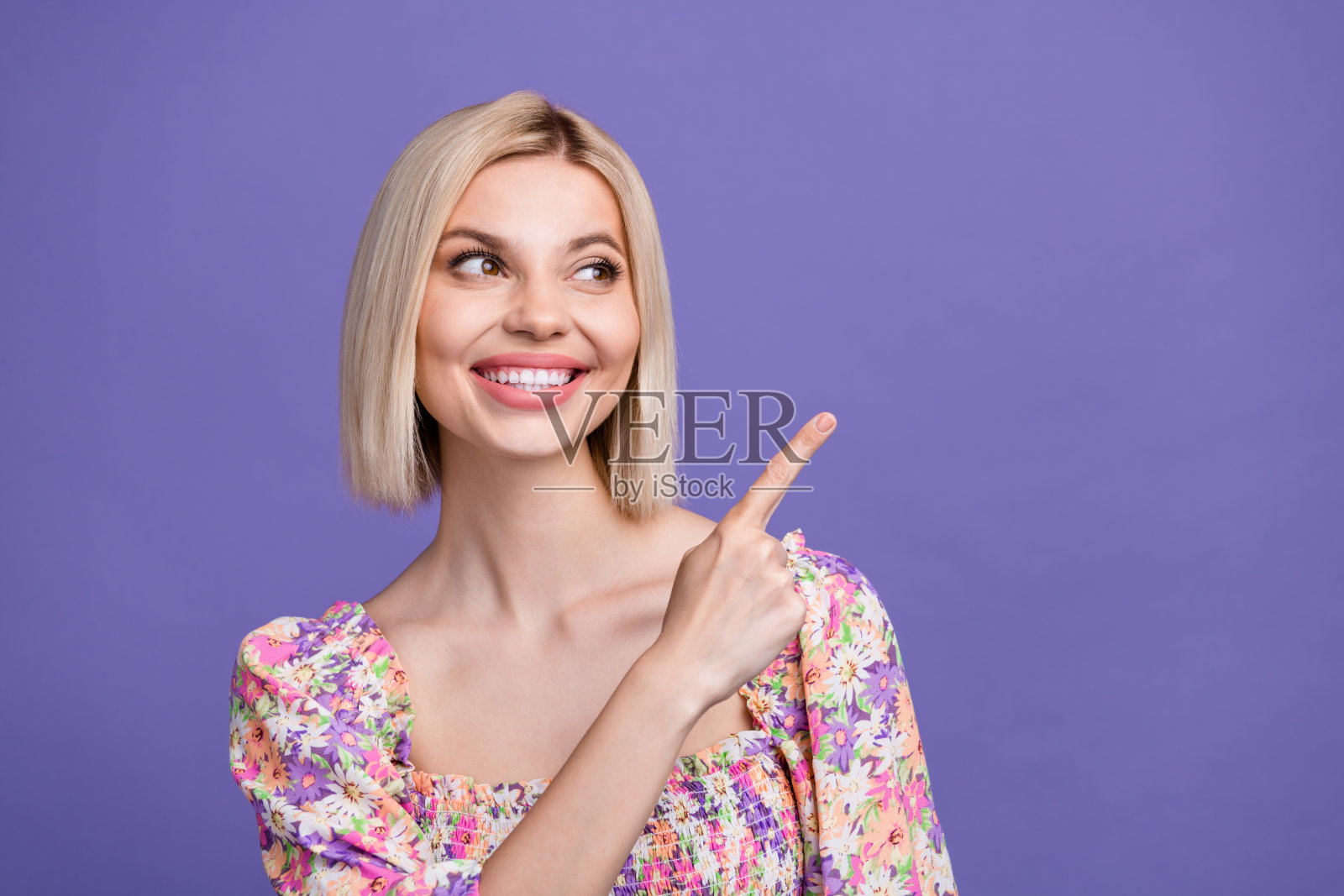 照片心情好可爱的女人穿着印花衬衫指着手指看空空间孤立的紫色背景照片摄影图片