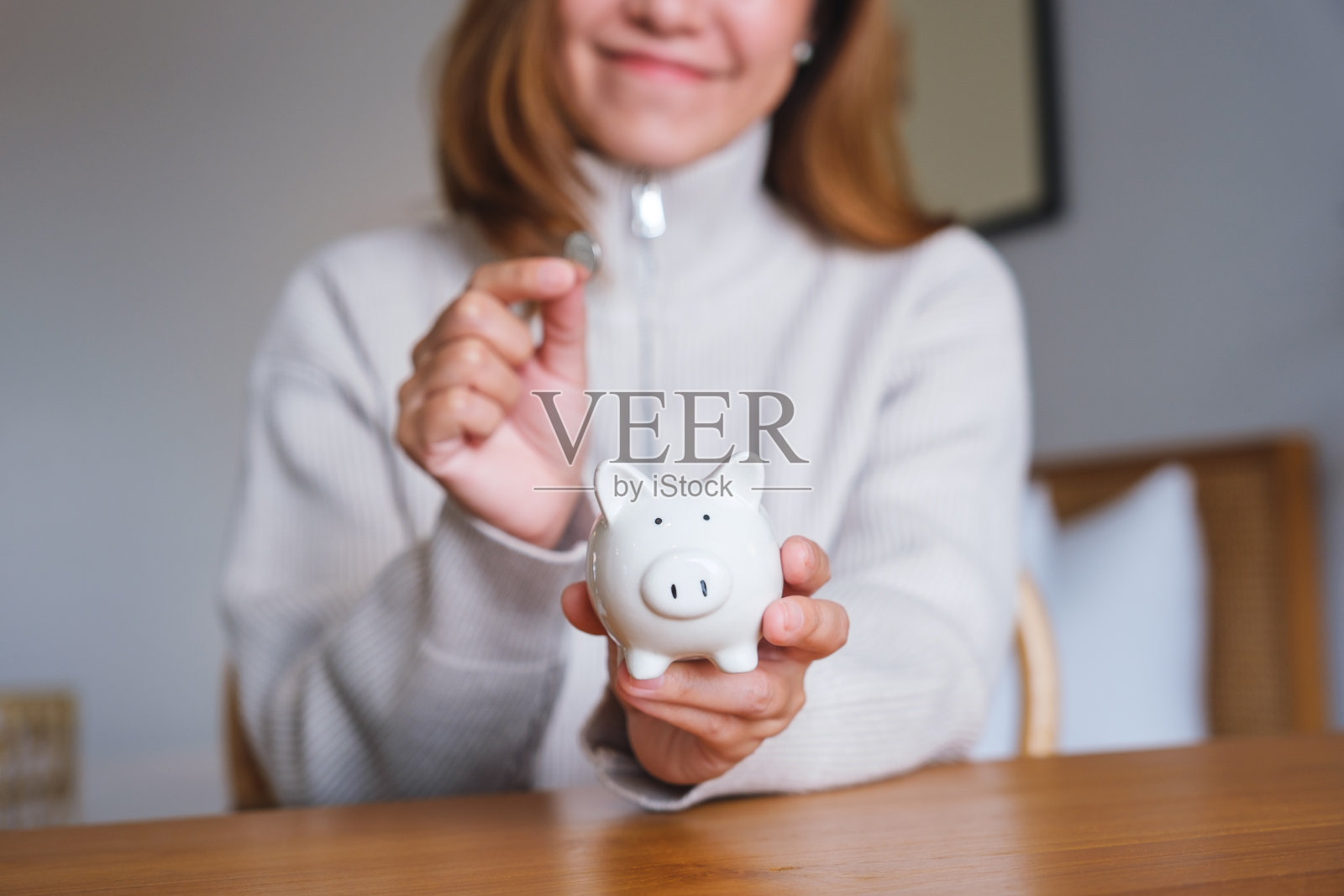 一名年轻女子手持硬币并放入存钱罐的特写图片照片摄影图片