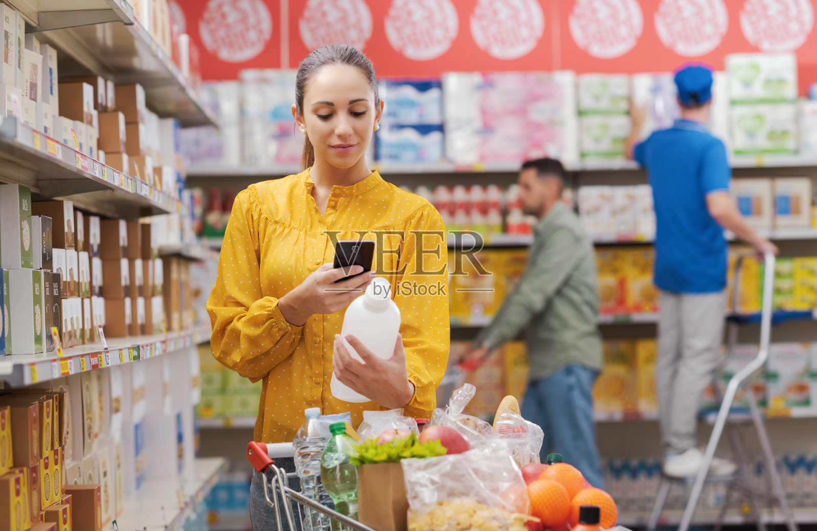 一位女士在超市用智能手机查看商品信息照片摄影图片