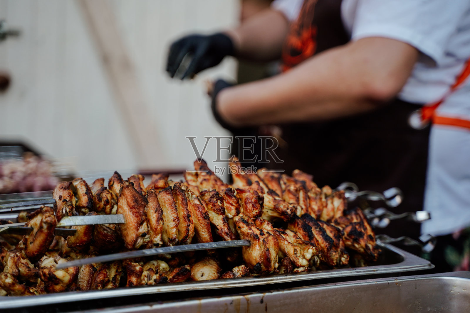 厨师烤着多汁的鸡肉，创造了一道咝咝作响的杰作。烹饪艺术的展示，捕捉精髓的烧烤在一个美味的奇观。照片摄影图片