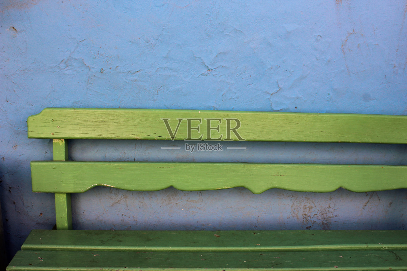 绿色的长凳，蓝色的墙照片摄影图片