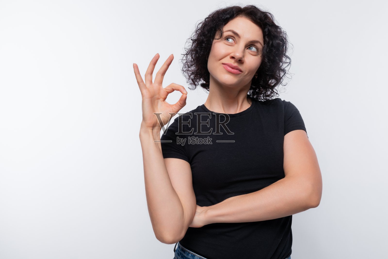 穿着黑色t恤的欧洲成年卷发女人，笑得很可爱，做着鬼脸照片摄影图片