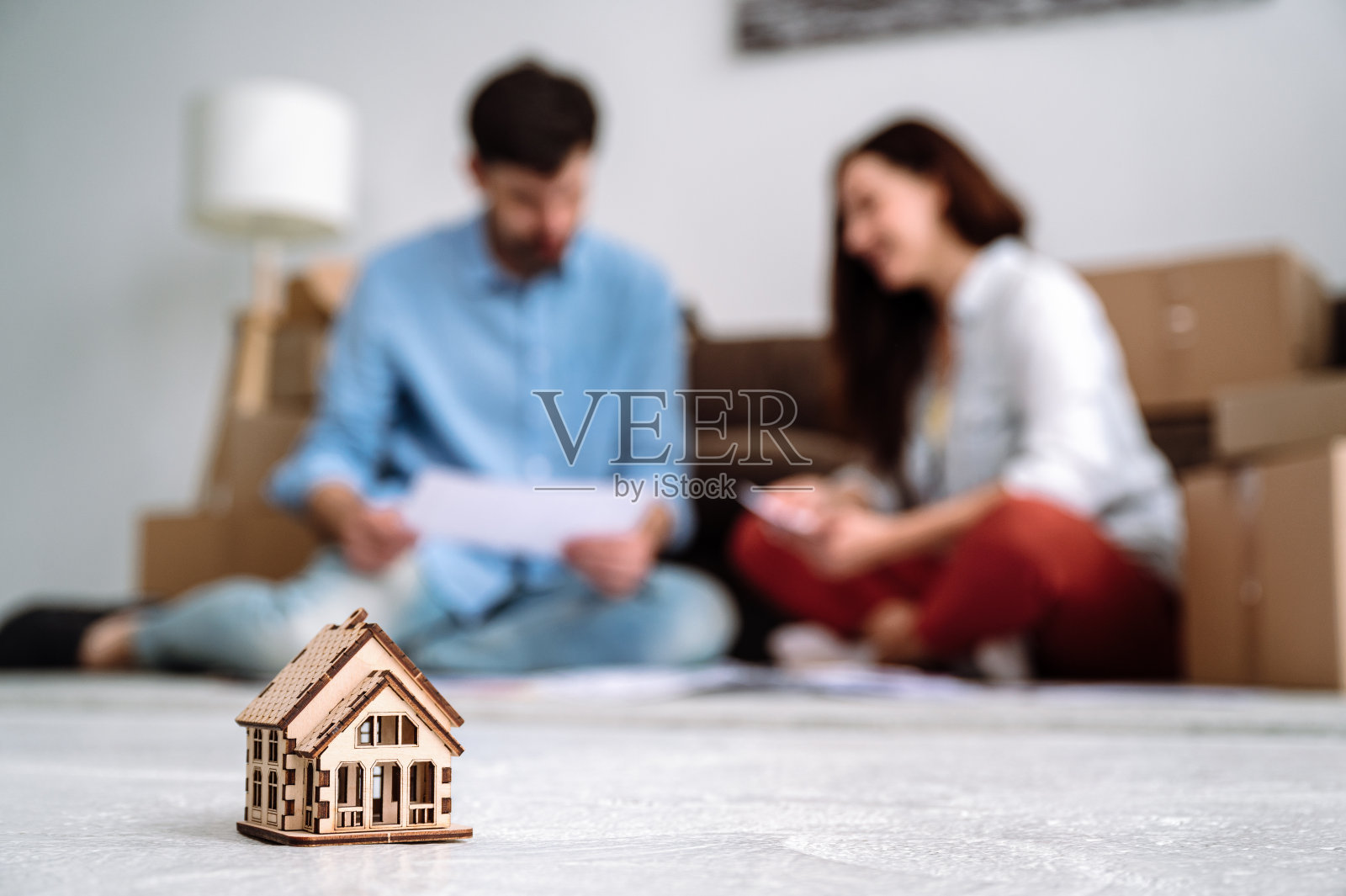 选择性地聚焦在小玩具屋和模糊的背景上，地板上有一对夫妇照片摄影图片