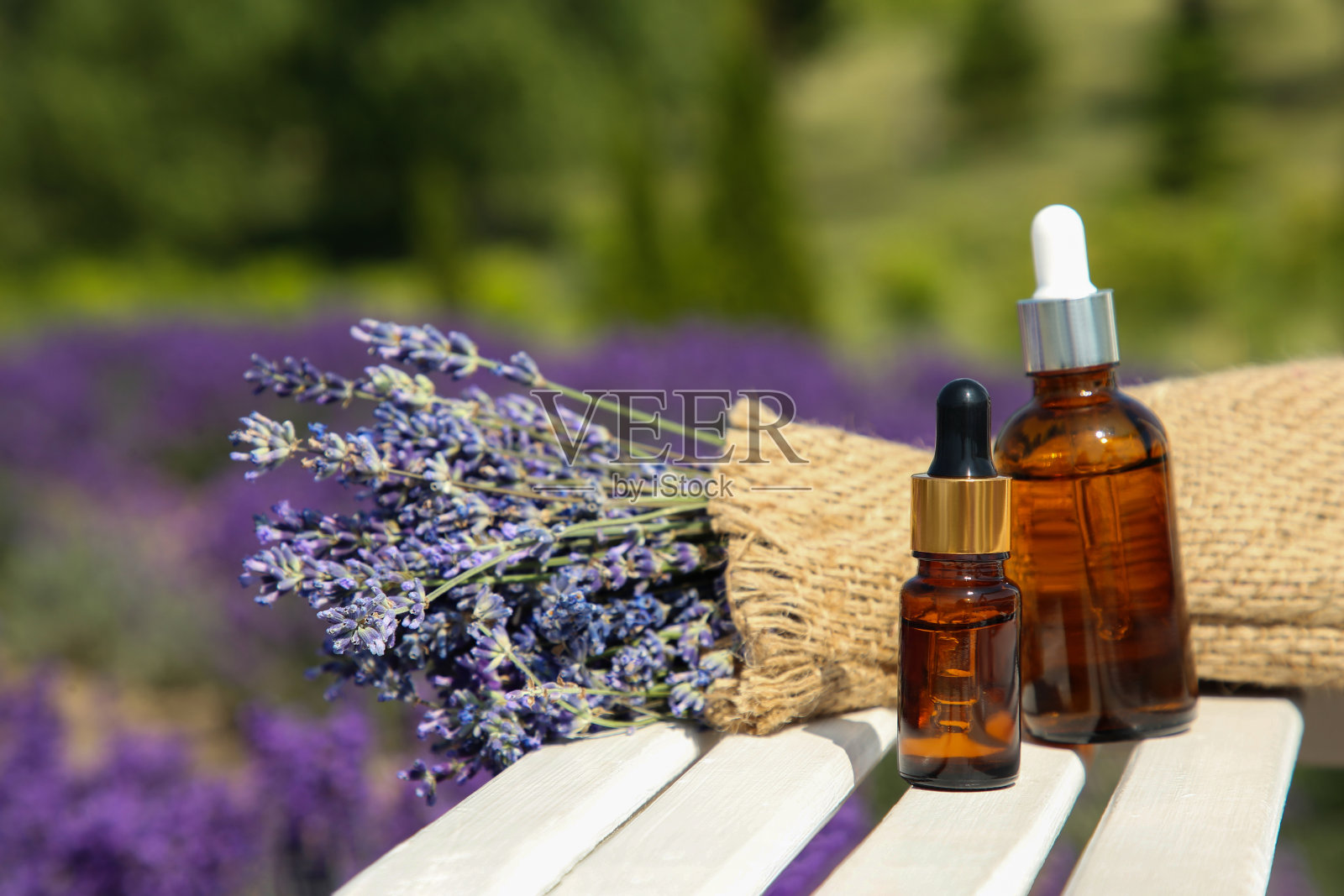 户外白色木质表面上的精油瓶和薰衣草花，为文字留出空间照片摄影图片