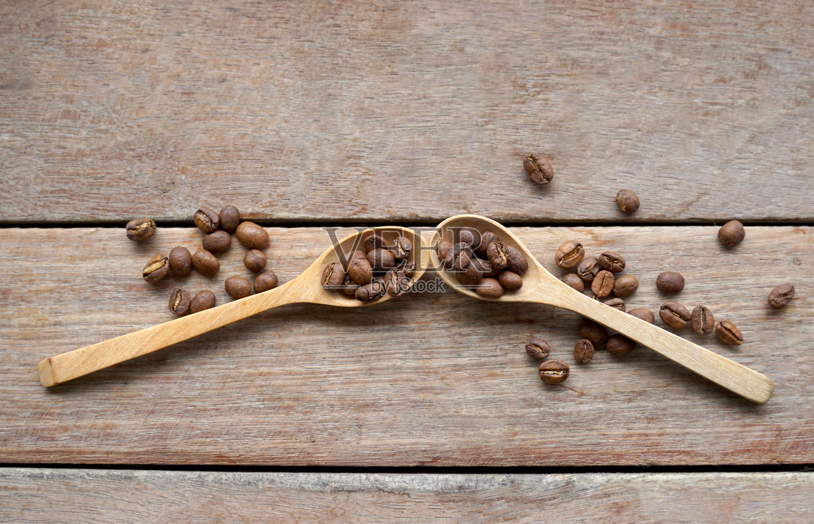 用木勺烤熟的咖啡豆，铺在木桌背景上。照片摄影图片