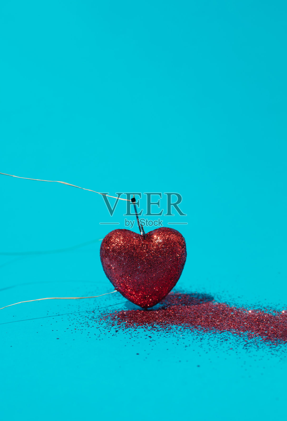 蓝色背景上的鱼钩上有一颗红色的心和闪闪发光的血。爱的概念。本空间照片摄影图片