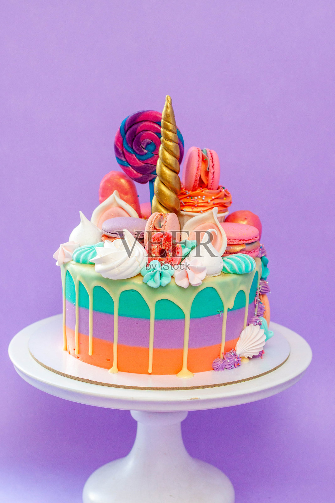 绿色、紫色和橙色的独角兽蛋糕，配上马斯卡彭奶酪玫瑰糖霜、杏仁饼和金角。复制空间到侧面，纯紫色背景照片摄影图片