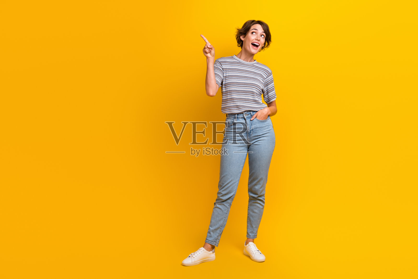 积极快乐的女孩穿着时髦的衣服，在黄色的背景上呈现空旷的空间照片摄影图片