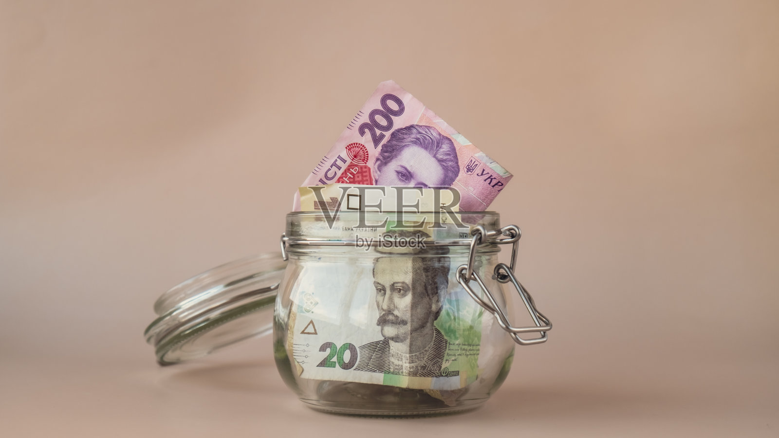 米色背景玻璃罐中的乌克兰格里夫纳现钞。储蓄观念、危机与通货膨胀、消费与经济。小费。额外的钱，被动的照片摄影图片