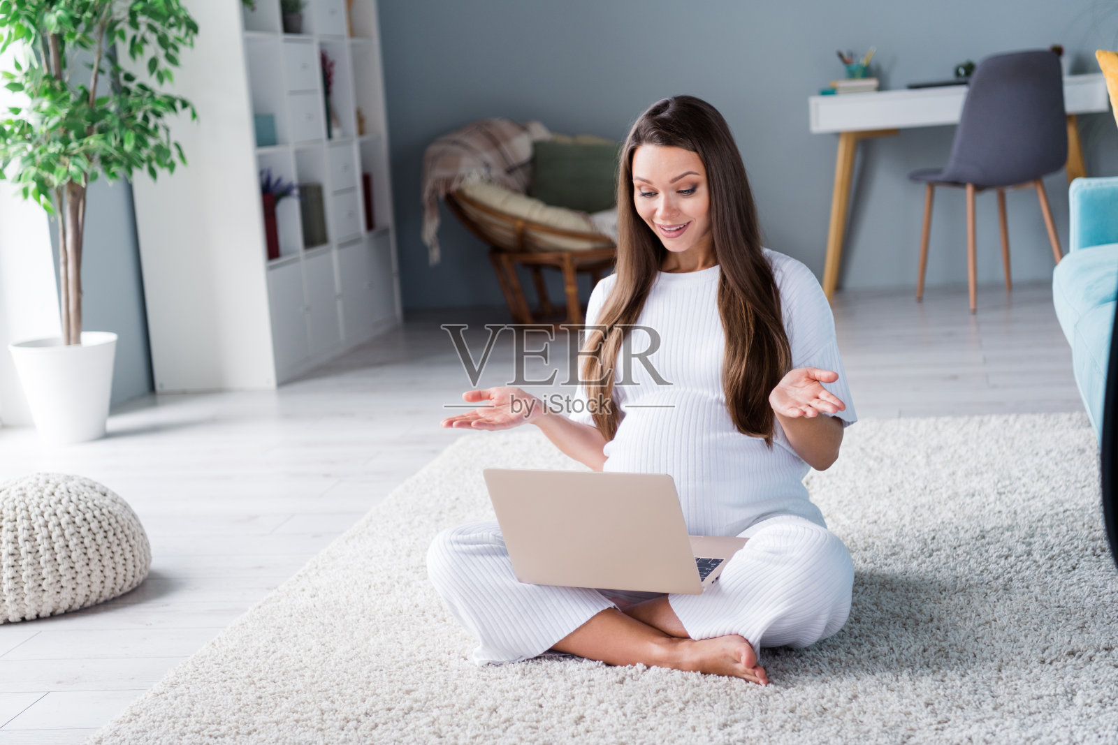 照片中甜美、漂亮、开朗的女孩怀孕了，未来的妈妈坐在地板上和丈夫在公寓里说话照片摄影图片