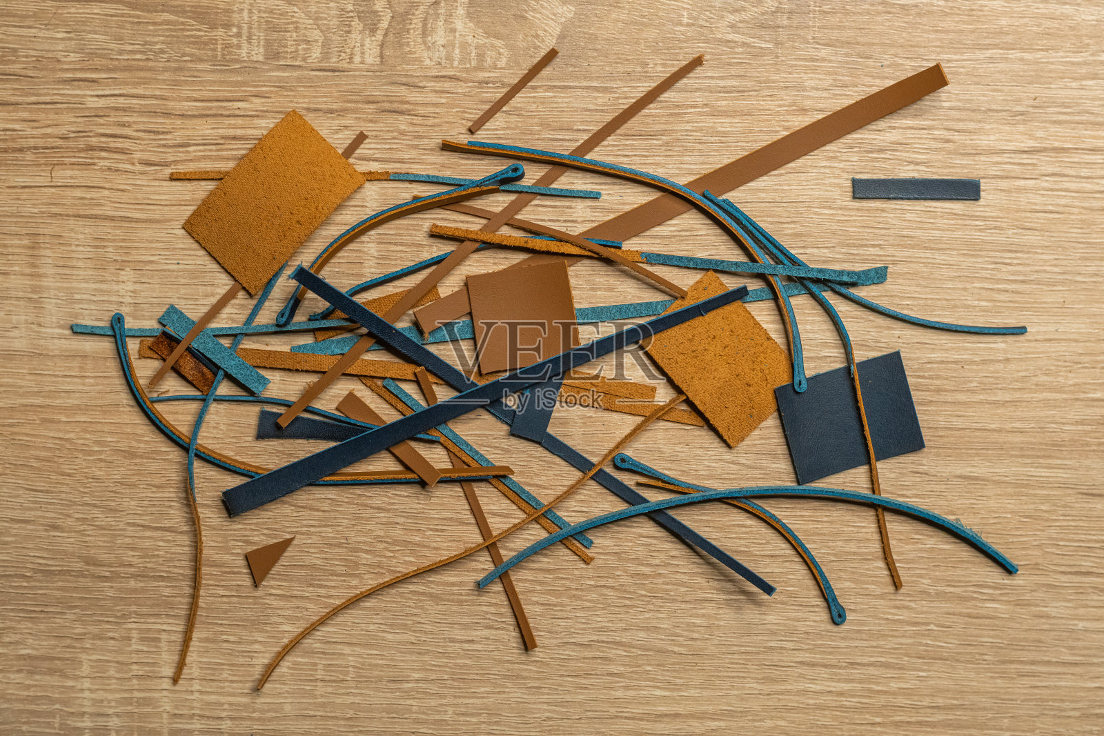 在木桌上制作真皮制品后的皮革废料。照片摄影图片