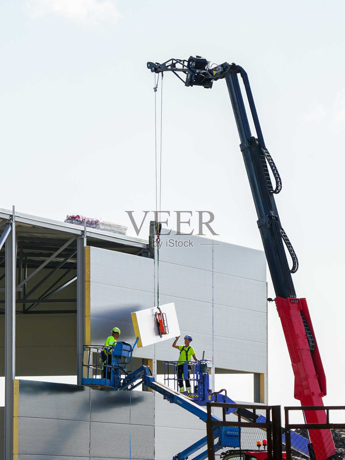 夹芯板墙装配使用伸缩臂起重机和两台自行式铰接升降机照片摄影图片