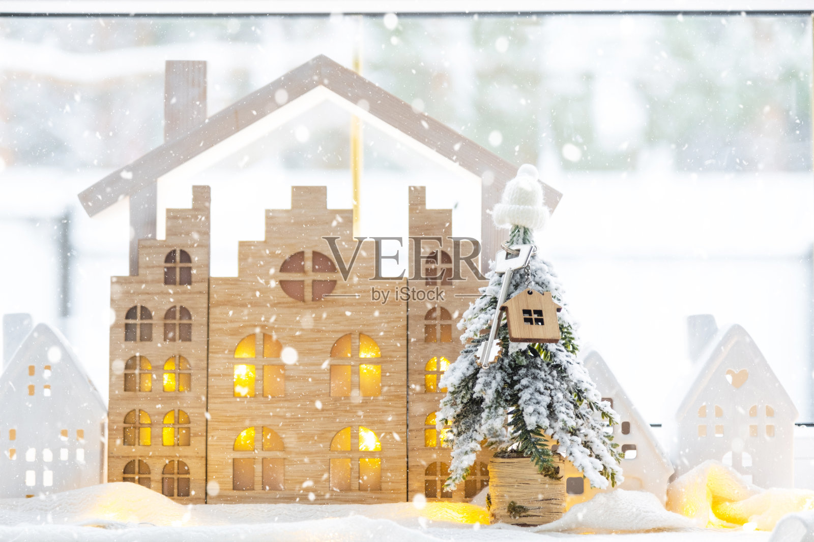 钥匙在圣诞树上，小房子在温馨的家，圣诞装饰在节日白色厨房的桌子上。新年礼物。保险，搬家，抵押贷款，租金和房地产照片摄影图片