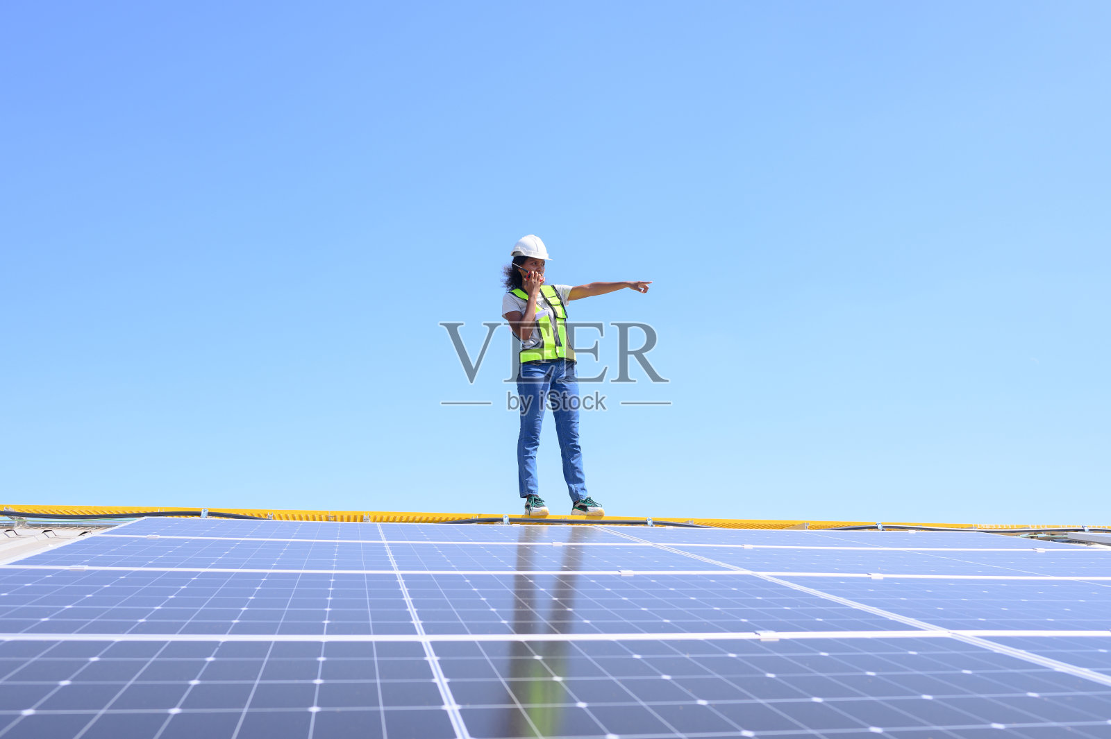 一位女工程师正在屋顶上安装太阳能电池板。在商业建筑屋顶上安装太阳能电池板或光伏电池的工程师或工人。照片摄影图片