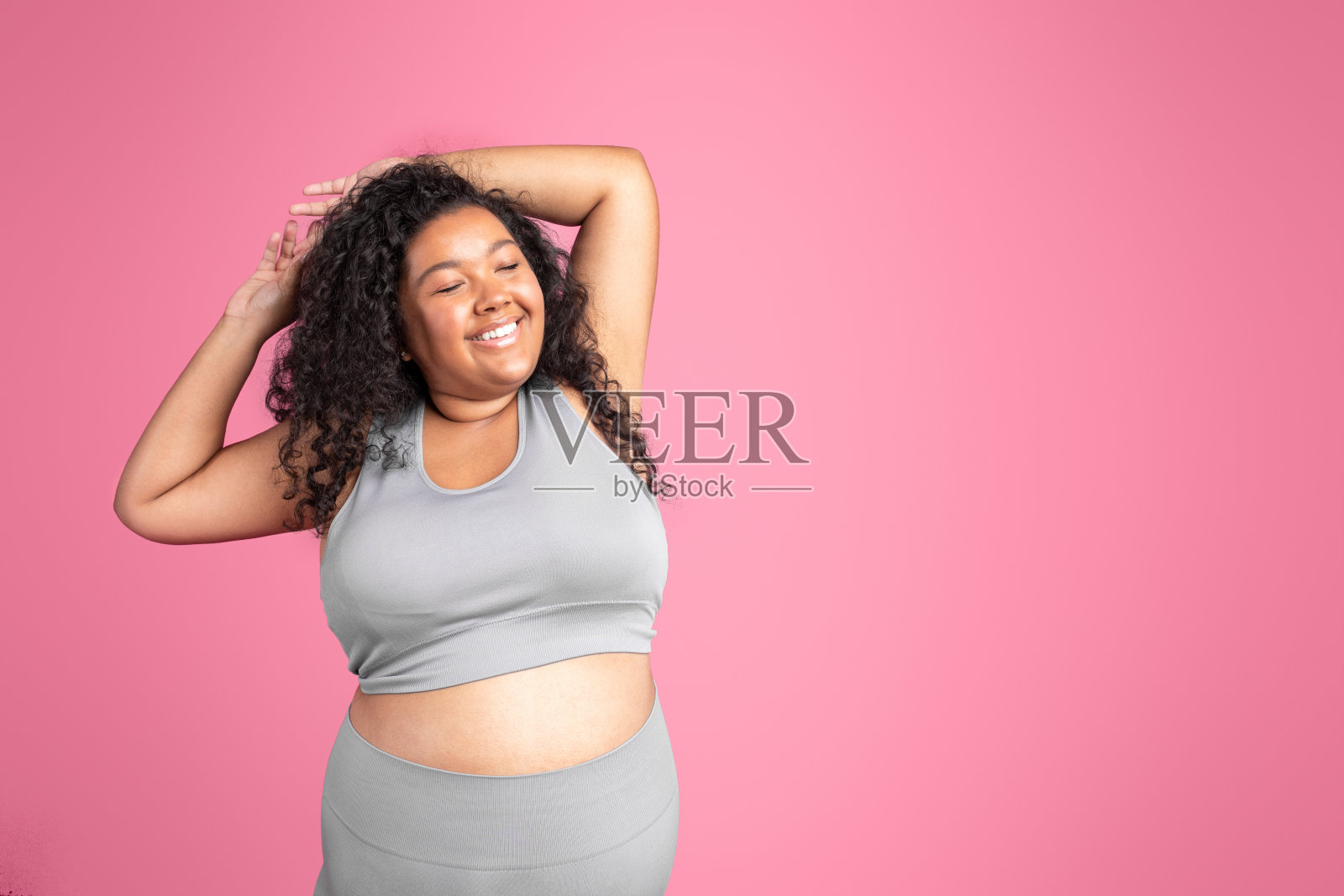 微笑的黑色身体积极女士在运动服举起手臂和伸展，享受锻炼效果，复制空间照片摄影图片