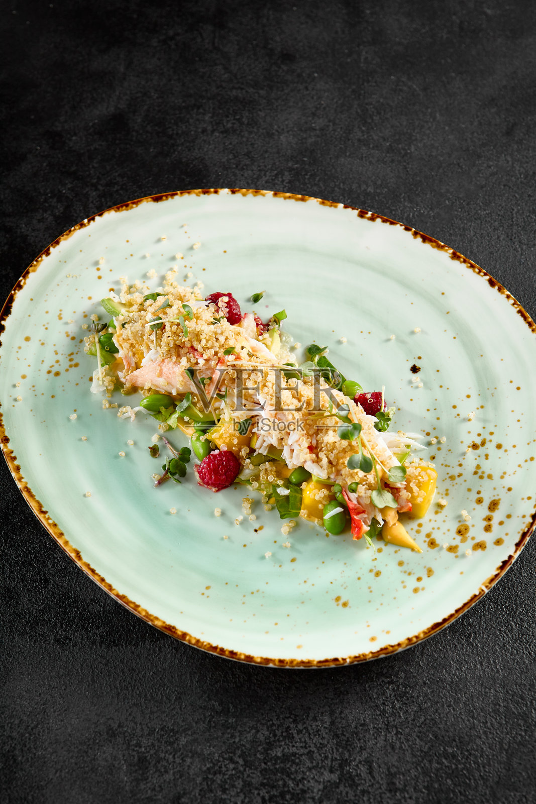 优雅的牛油果沙拉，蟹，藜麦，巧妙地安排在一个斑点绿松石盘照片摄影图片