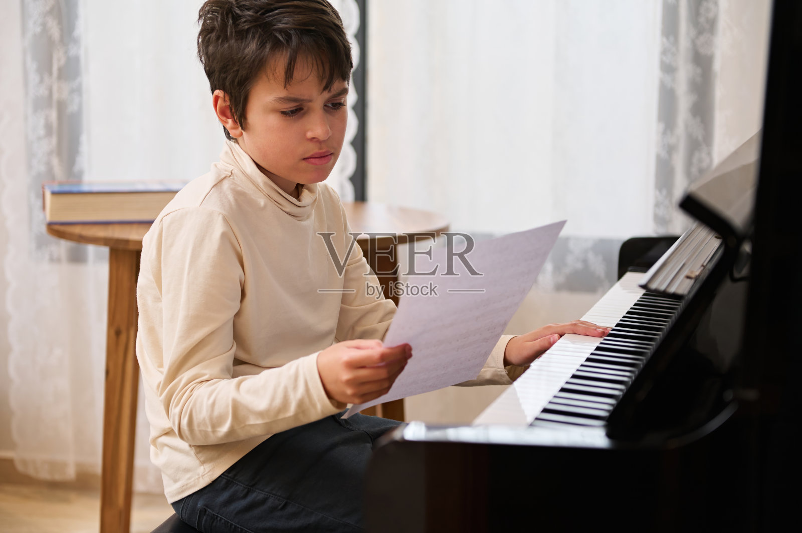 可爱的青春期前的男孩，钢琴家音乐家触摸钢琴键盘，学习音符在音乐课在家里照片摄影图片