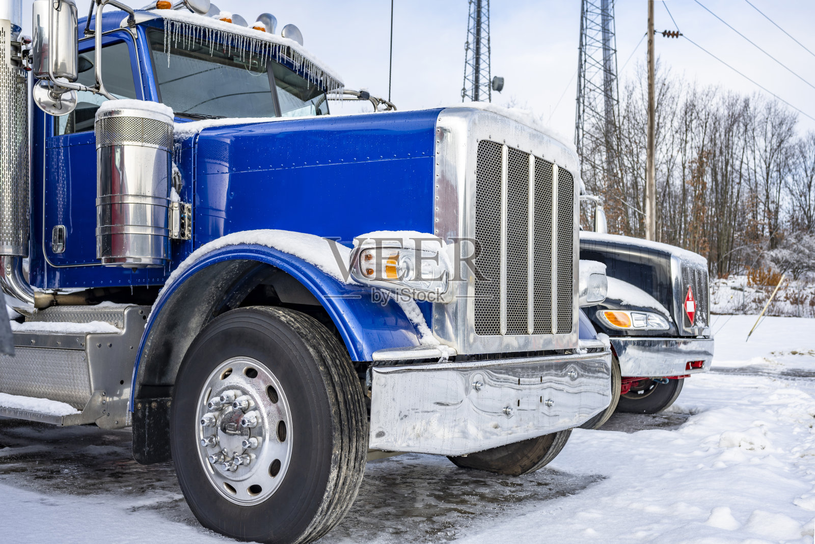 明亮的蓝色驾驶室大钻机半卡车与铬零件站在卡车停车停车场覆盖着冰雪在冬天的时候照片摄影图片
