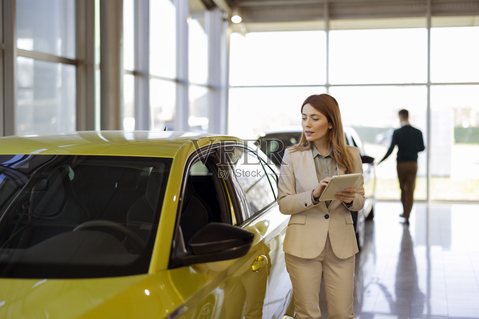 汽车陈列室里拿着数码平板电脑的女售货员照片摄影图片