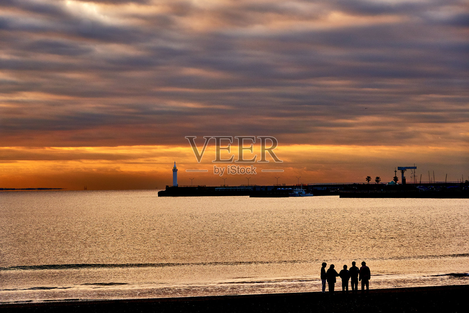 日出时人们站在风景优美的海滩上照片摄影图片