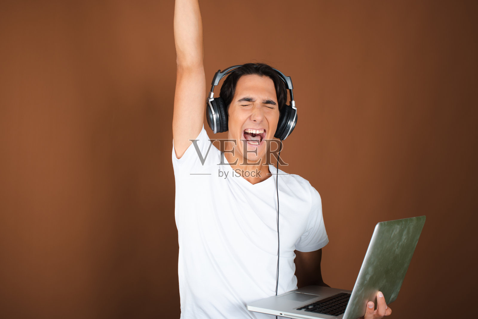 一个年轻漂亮的学生在笔记本电脑前工作，听音乐。照片摄影图片