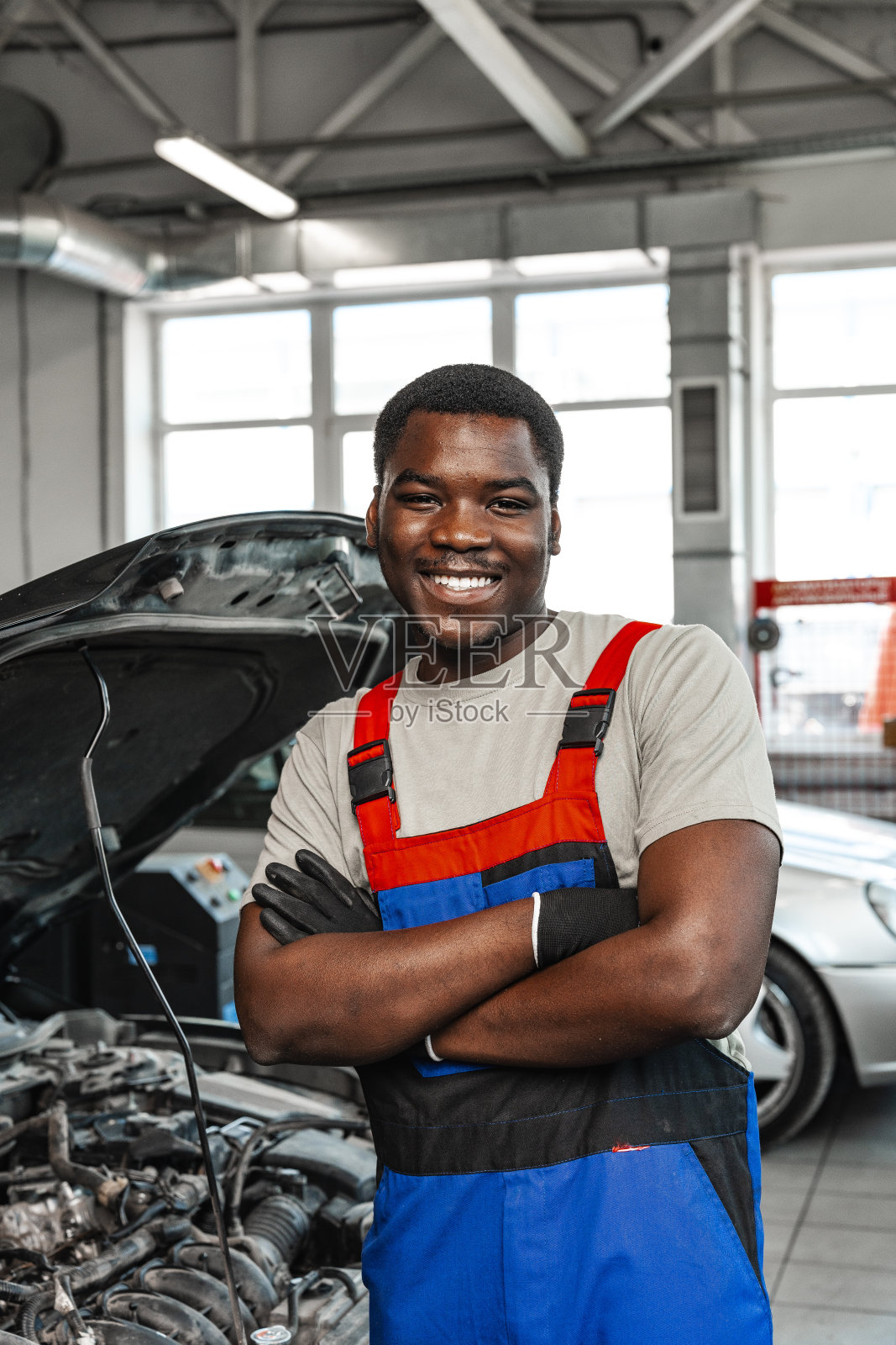 穿着制服站在车库里的非洲青年汽车服务工人的肖像照片摄影图片