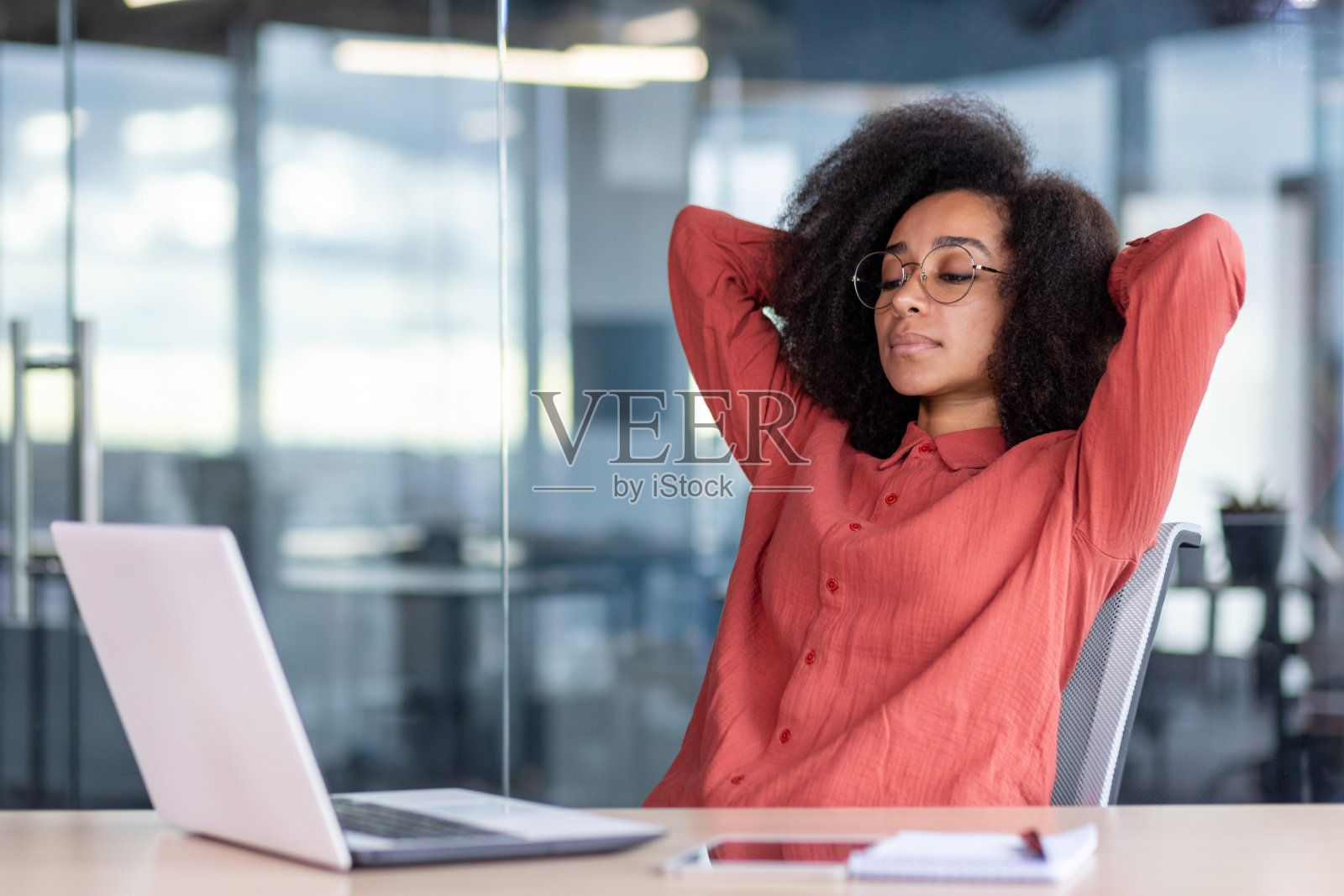 出色地完成了工作项目的女性，微笑着放松地看着笔记本电脑屏幕的女商人，双手放在脑后的女工在办公室休息，微笑着做梦和思考照片摄影图片