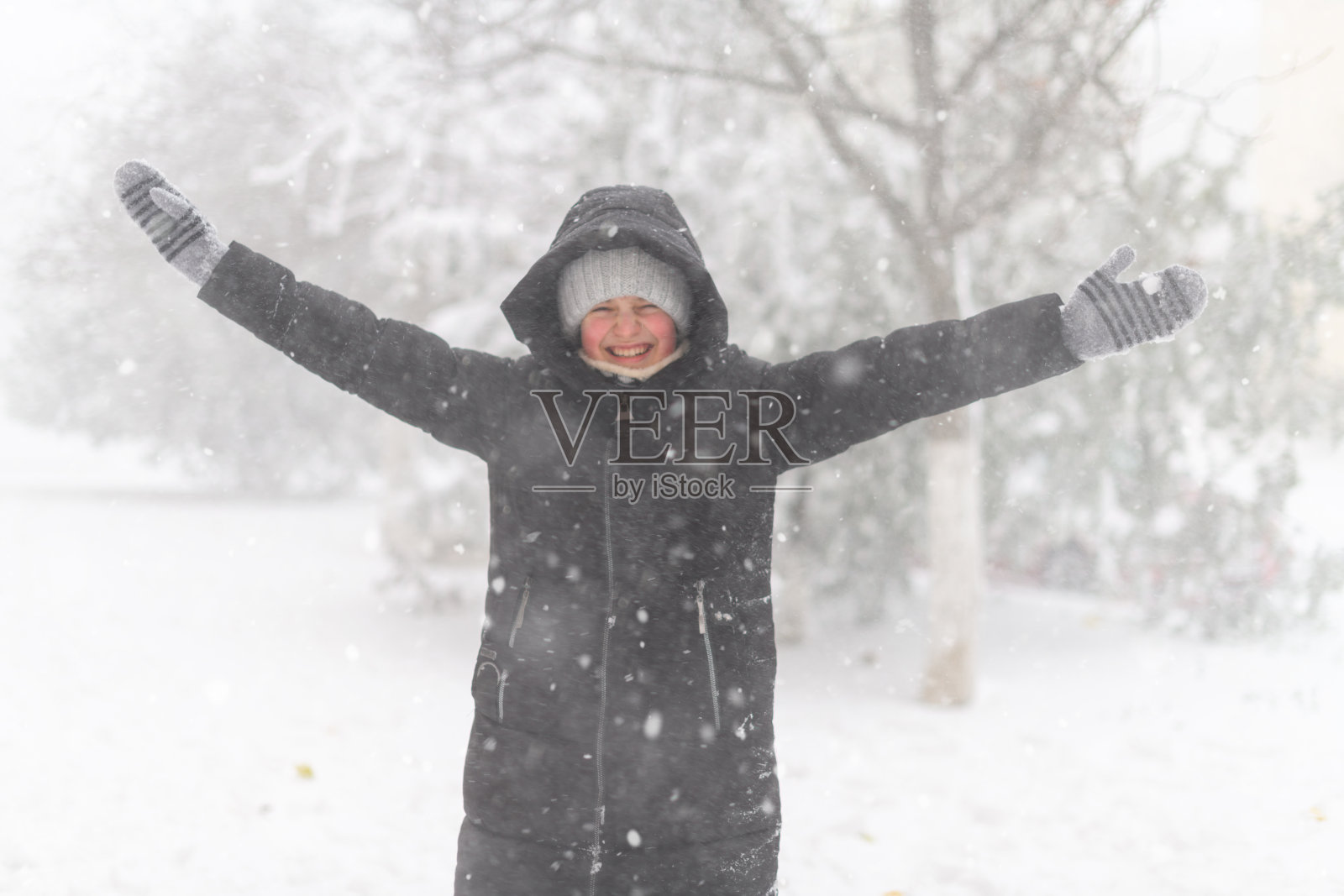 一个女孩在街上玩雪，这是一个下雪的冬天，暴风雪和霜冻照片摄影图片
