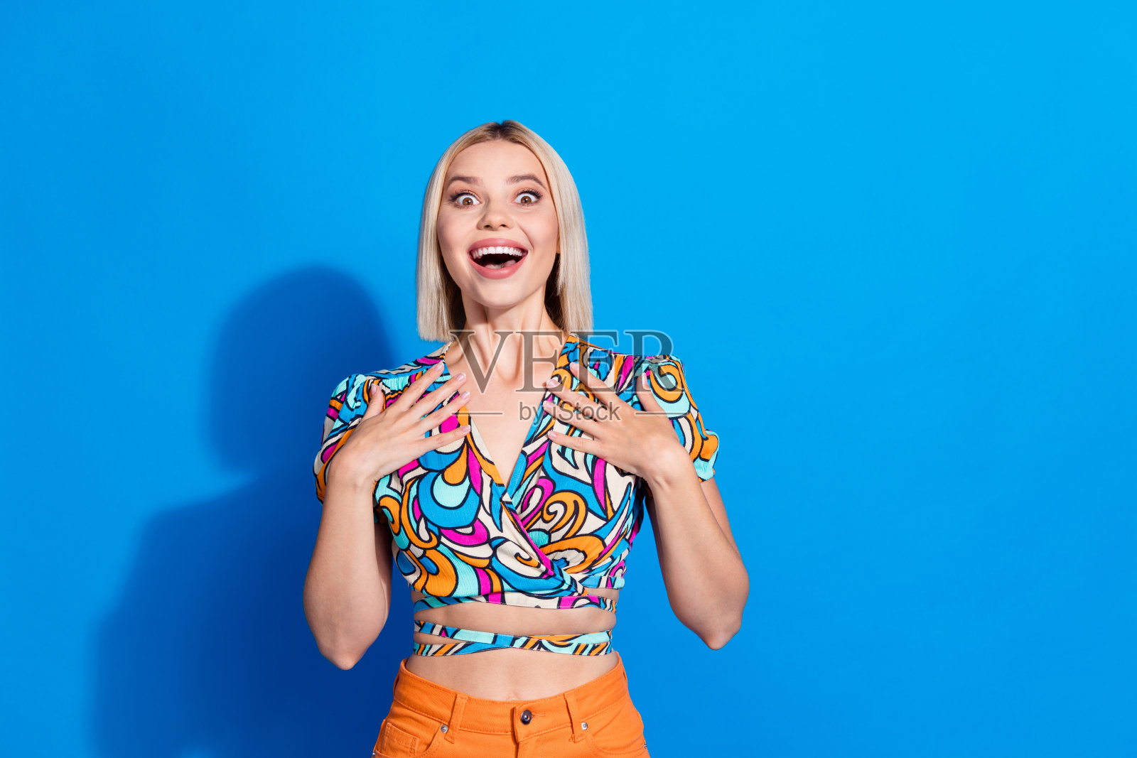 肖像的华丽惊讶的女孩双手触摸胸部不能相信空白的空间和孤立的蓝色背景照片摄影图片