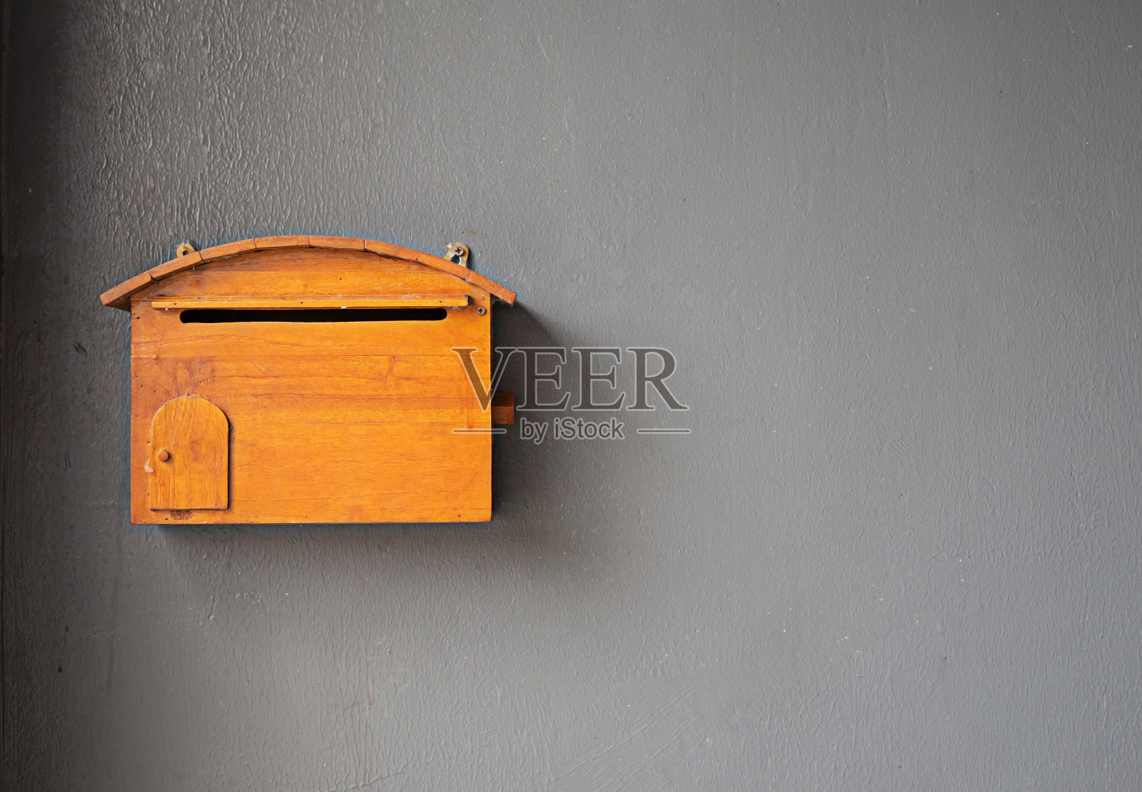 一个装在灰色墙上的木制邮筒。照片摄影图片