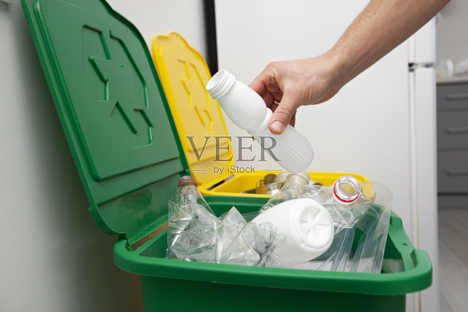 这个人把塑料瓶扔进了三个分拣垃圾的容器中的一个照片摄影图片