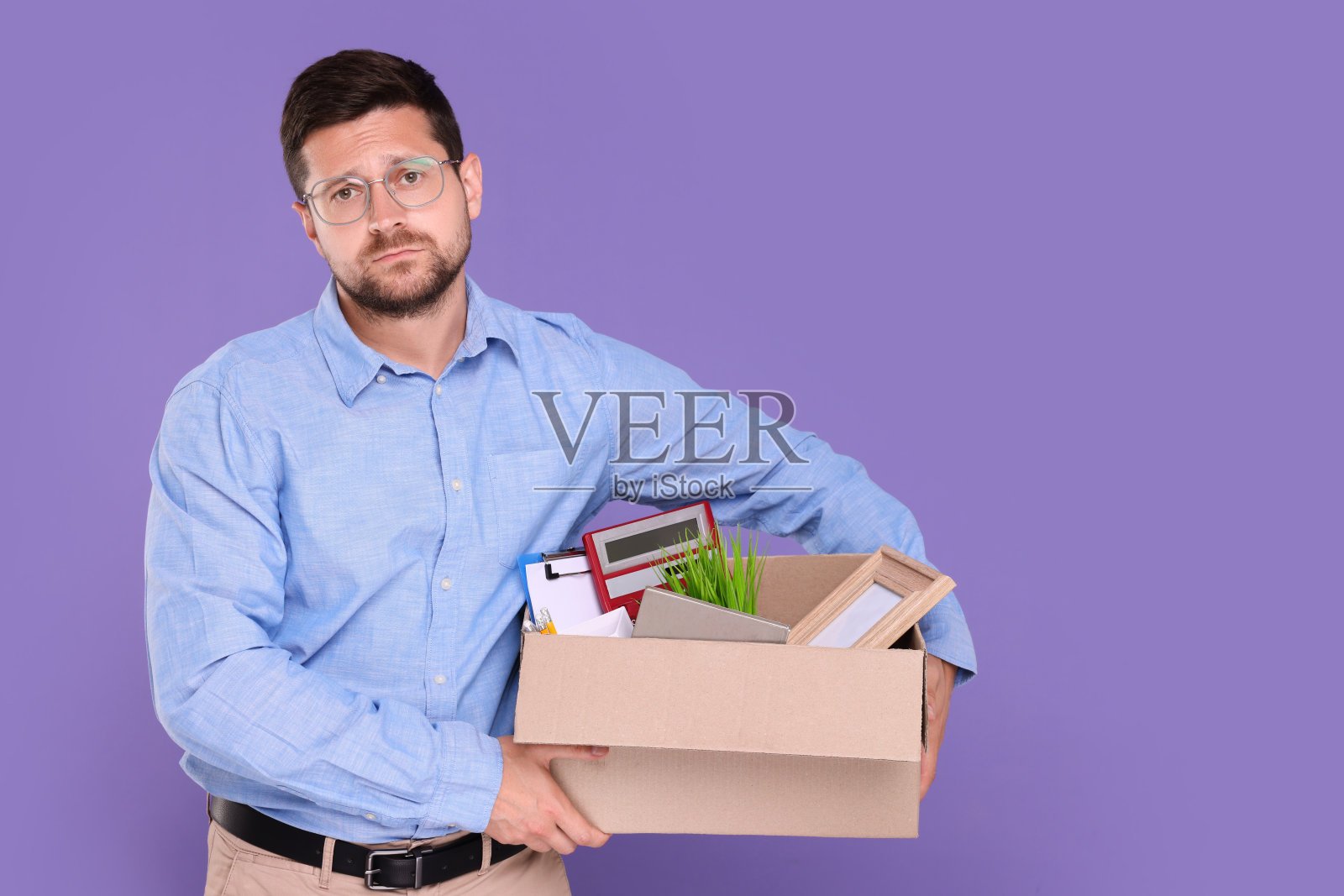 失业男子抱着装有个人办公物品的盒子，背景为紫色，有文字空间照片摄影图片