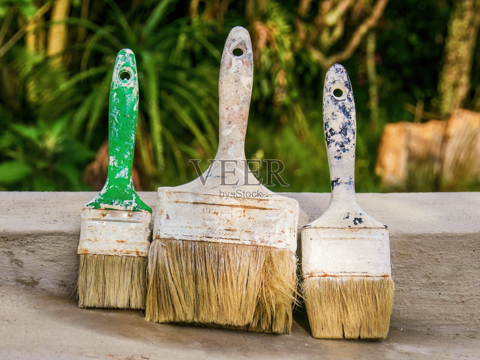 三把非常常用的油漆刷在水泥水箱上干燥的特写照片摄影图片