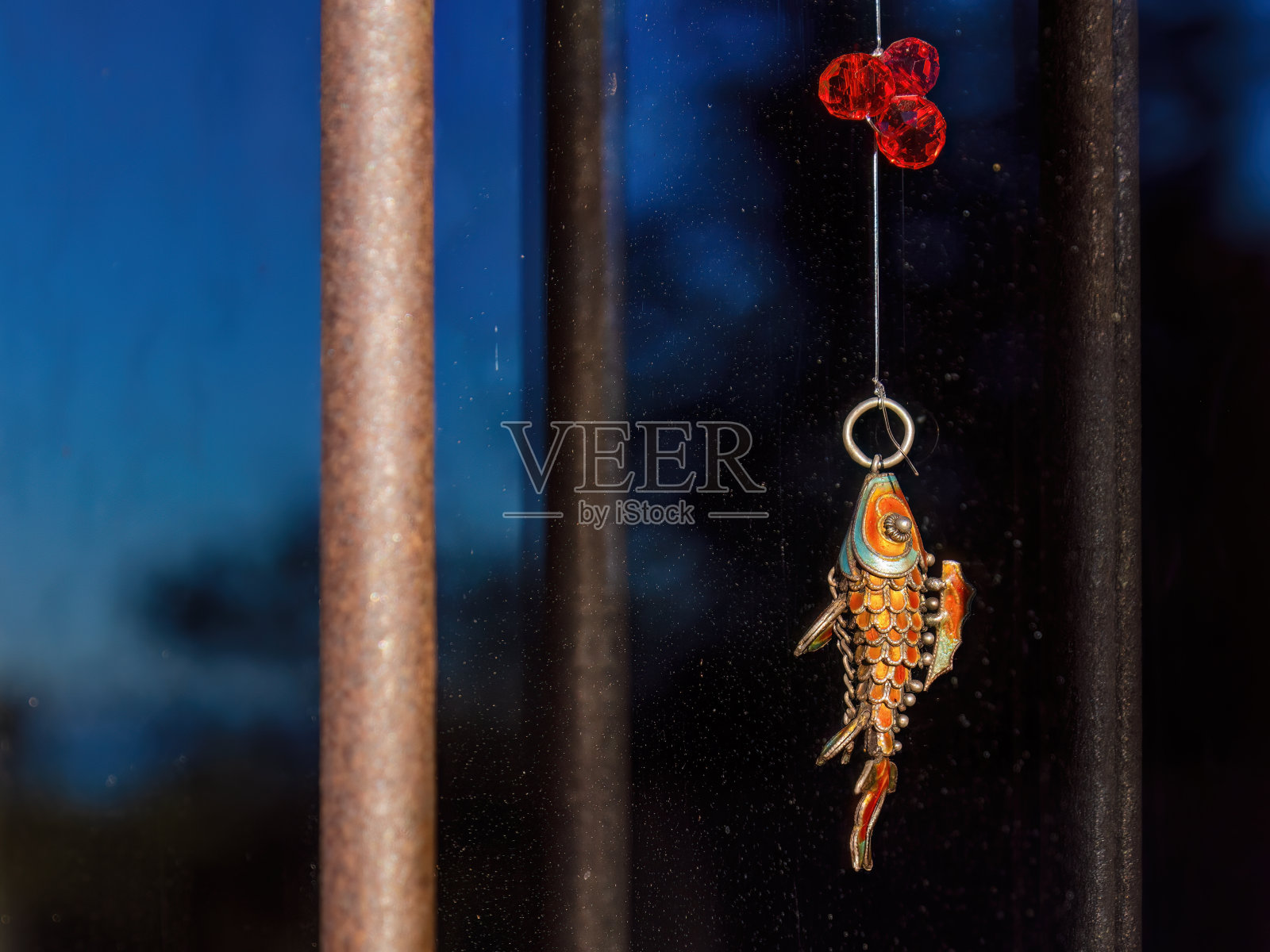 一条五颜六色的金属鱼，上面有三颗红色的塑料豆照片摄影图片